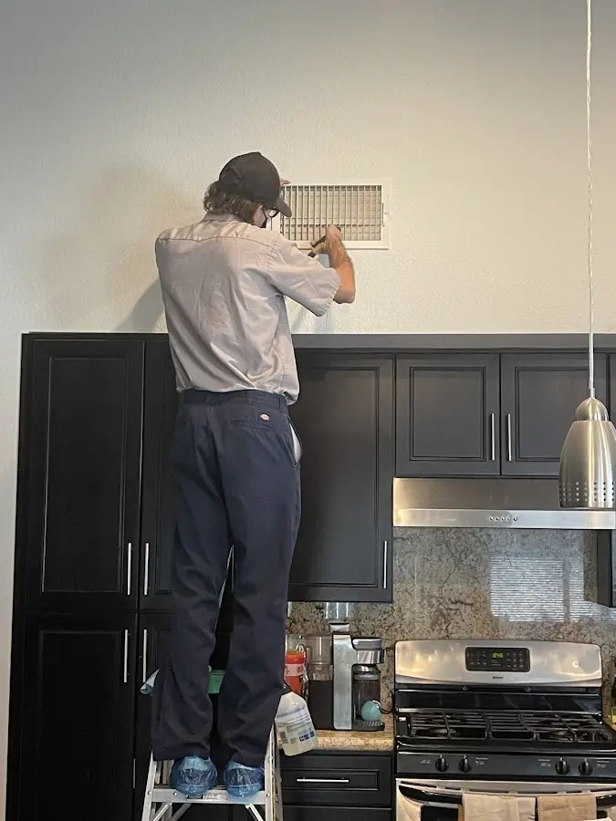 Technician inspecting an air vent during HVAC service in Arkadelphia